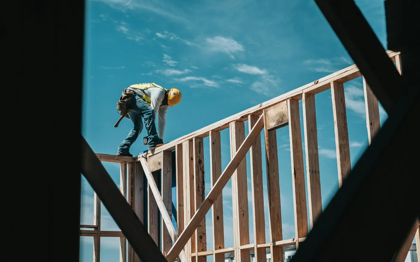construction worker in hard hat on building frame by Josh Olalde courtesy of Unsplash.