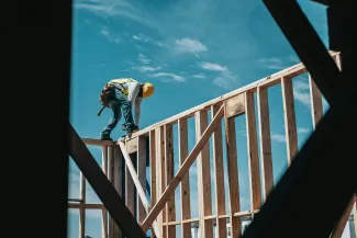 construction worker in hard hat on building frame by Josh Olalde courtesy of Unsplash.