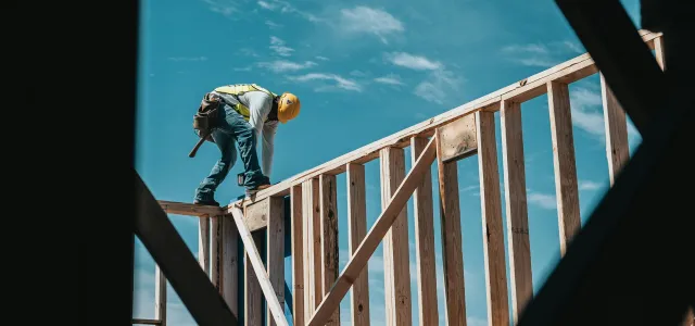 construction worker in hard hat on building frame by Josh Olalde courtesy of Unsplash.
